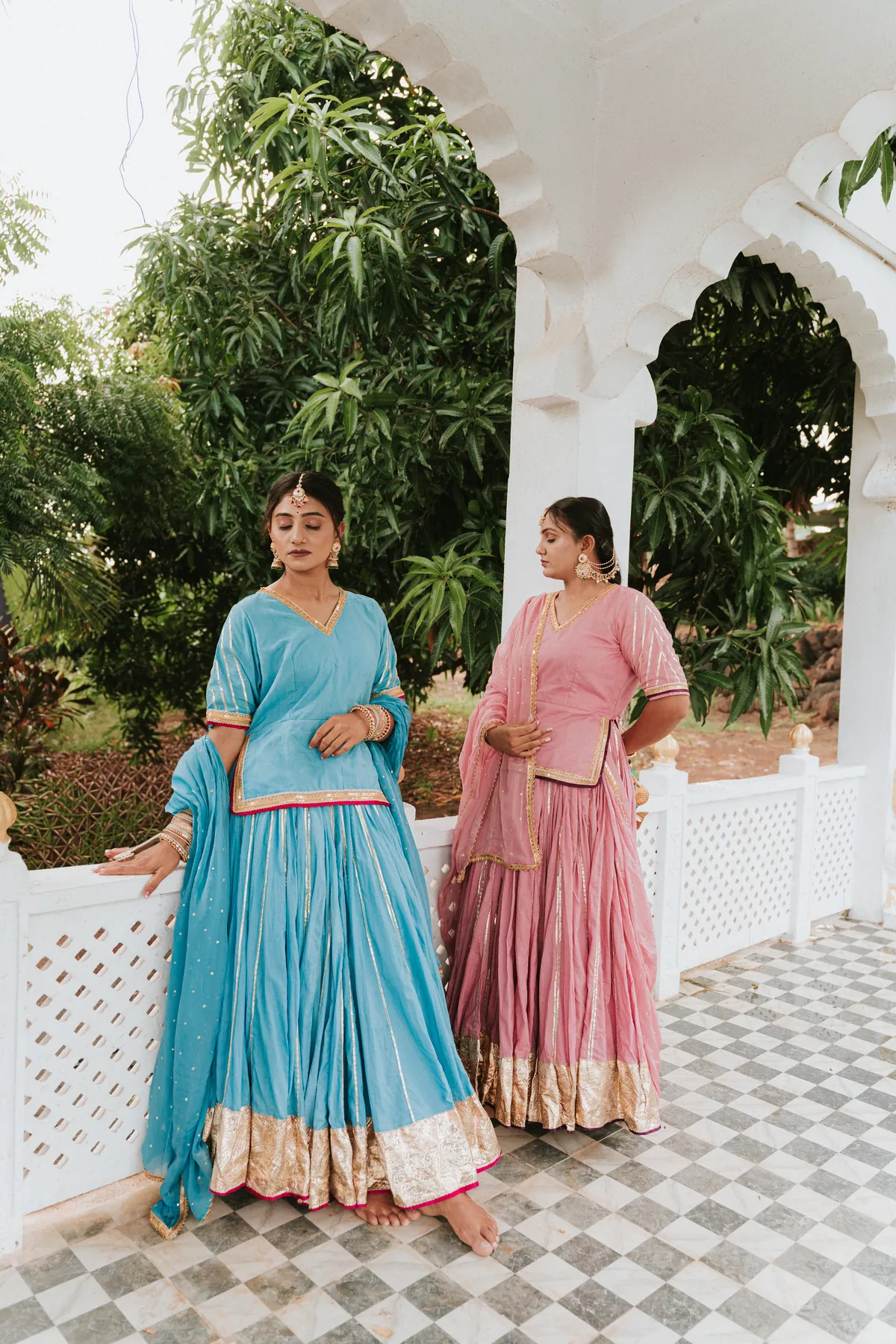 Traditional fashion portraits beneath white arches and green trees